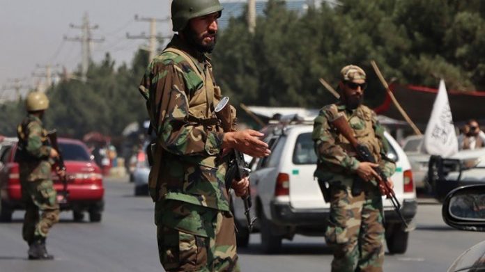 Taliban roam the streets with a man hanging from the neck of two car tires he had stolen